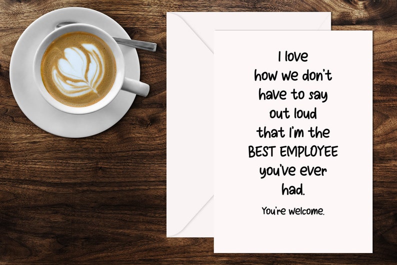 May include: A white greeting card with black text that reads: I love how we don't have to say out loud that I'm the BEST EMPLOYEE you've ever had. You're welcome. The card is placed next to a white envelope and a white ceramic cup of coffee.