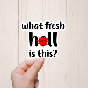 May include: A white sticker with black text that reads "what fresh hell is this?" with a red circle with a white star and the word "OOPS!" inside the circle.