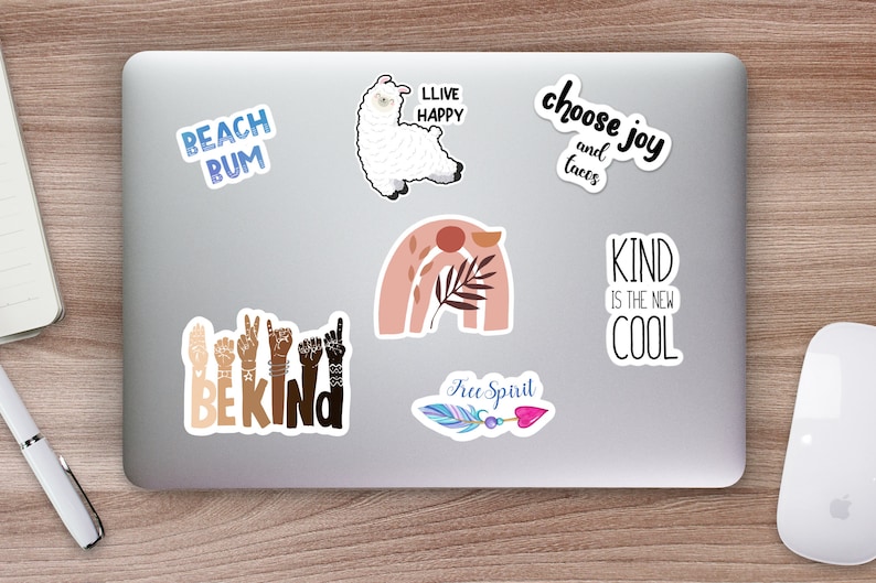 May include: A laptop computer with several stickers on it. The stickers feature various designs and phrases, including a llama, a rainbow, a feather, and the words "Beach Bum", "Live Happy", "Choose Joy and Tacos", "Be Kind", "Kind is the New Cool", and "Free Spirit".