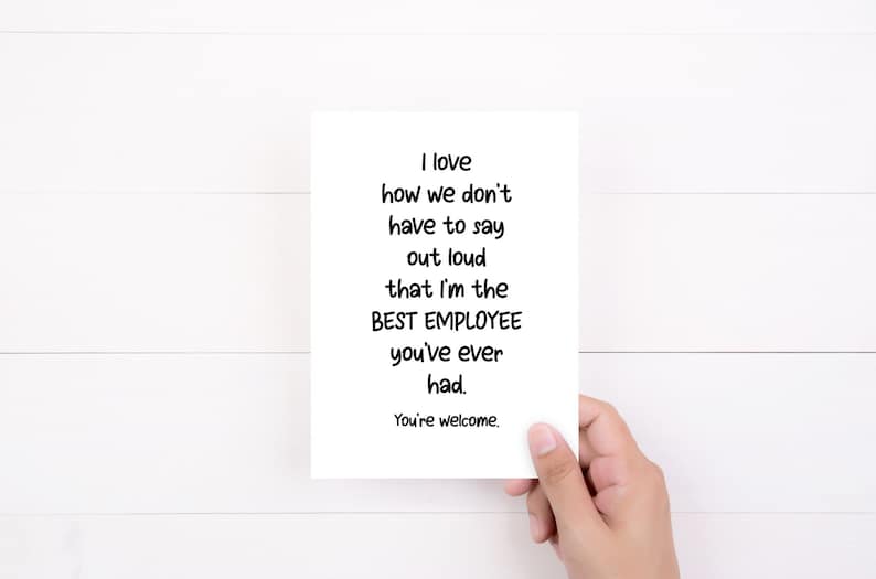 May include: A white rectangular greeting card featuring black text that reads: I love how we don't have to say out loud that I'm the BEST EMPLOYEE you've ever had. You're welcome. The card is held against a plain white background.
