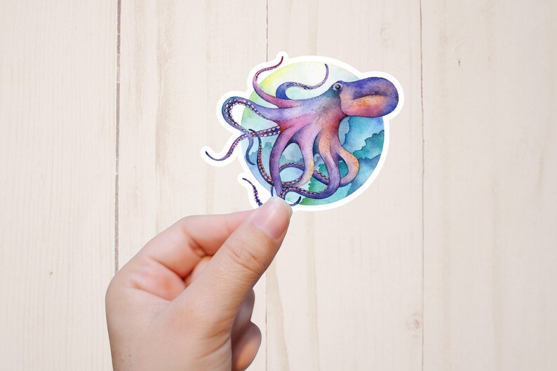 May include: A watercolor illustration of a purple and pink octopus with eight tentacles, swimming in a blue and green ocean. The octopus is surrounded by a white circle.