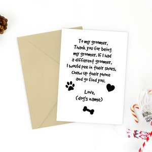 May include: A greeting card with a humorous message for a dog groomer, accompanied by a tan envelope. The card features a paw print, heart, and bone graphic. Christmas decorations, including candy canes and ornaments, surround the card.
