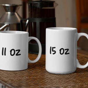 Puede incluir: Dos tazas de cer&aacute;mica blanca con letras negras. La taza de la izquierda dice "11 oz" y la taza de la derecha dice "15 oz".