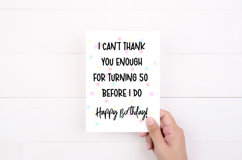 Może przedstawiać: Biała kartka urodzinowa z napisem "I can't thank you enough for turning 50 before I do. Happy Birthday!" trzymana w dłoni. Karta ma kolorowe kropki.