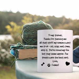 Puede incluir: Taza de cer&aacute;mica blanca con texto negro que dice "To my trainer, Thanks for teaching me all that stuff my humans want me to do - sit, stay, heel, come, drop it. You've ruined my fun but they seem happier. The treats were the best part. Love, (name)" con una huella de pata y un hueso.