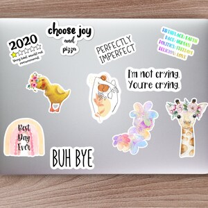 K&ouml;nnte beinhalten: Eine Sammlung bunter Aufkleber mit verschiedenen Designs und Spr&uuml;chen, darunter ein Regenbogen mit dem Text "Best Day Ever", ein gelbes Entenk&uuml;ken mit Blumen, eine Giraffe mit einer Blumenkrone, eine Hand mit dem Text "Perfectly Imperfect" und der Text "Choose Joy and Pizza".