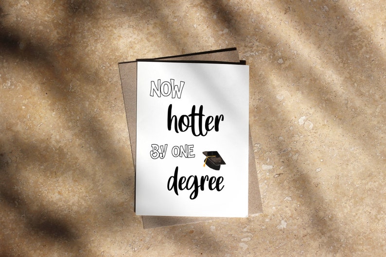 May include: A graduation card with the words "Now hotter by one degree" in black script. A small graduation cap illustration is below the text. The card is white and set against a neutral background.