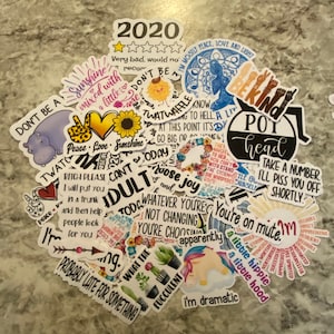 Pu&ograve; includere: Una collezione di adesivi colorati con varie frasi e disegni, tra cui "Don't Be A Twatwaffle", "Peace Love Sunshine", "Pot Head", "I'm Dramatic", "You're On Mute", "A Little Hippie", "A Little Hood", "2020", "Probably Late For Something", "What The", "Today I Choose Joy", "Whatever You're Not Changing", "You're Choosing Apparently", "Bitch Please I Will Put You In A Trunk And Then Help People Look For You", "Take A Number I'll Piss You Off Shortly", "I'm Mostly Peace Love And Light", "The Magic To Her You Can't With Stand The Storm She Whispered Back", "I'll Stand Up For Myself", "I'm A Little Spoiled", "Motivated", "Resourceful", "Valuable", "Reliable", "Appreciative", "Present", "Successful", "Worthy", "Motivated", "Free Spirited", "I'm A Little Spoiled", "Motivated", "Resourceful", "Valuable", "Reliable", "Appreciative", "Present", "Successful", "Worthy", "Motivated", "Free Spirited".