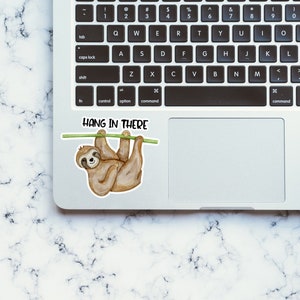 May include: A laptop computer with a sticker of a sloth hanging from a branch with the text "HANG IN THERE".