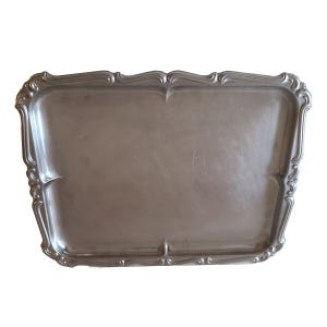 May include: A rectangular silver-toned metal serving tray with a smooth, flat center surface and a raised, decorative border featuring curved, scalloped edges and embossed detailing along the entire perimeter of the tray.