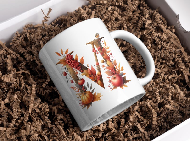 May include: White ceramic mug with a fall-themed design featuring the letter "W" surrounded by autumn leaves, berries, and a small pumpkin.