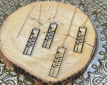 May include: Four threader earrings featuring a rectangular frame with a central stem and leaf design. Two earrings are silver-toned and two are gold-toned, each attached to a delicate box chain that pulls through the earlobe.