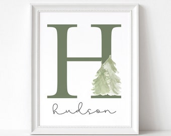 May include: A white framed print with a green letter H and two green watercolor trees. The name "hudson" is written in cursive below the letter. The text "make this day count" is written in cursive at the bottom of the print.