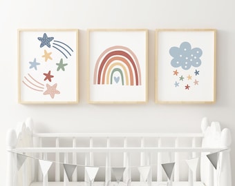 Könnte beinhalten: Drei gerahmte Drucke mit einem Kinderzimmer-Thema. Der erste Druck zeigt einen blauen und gelben Stern mit einem Sternschnuppen-Schwanz. Der zweite Druck zeigt einen Regenbogen mit einem Herzen in der Mitte. Der dritte Druck zeigt eine blaue Wolke mit Sternen, die aus ihr fallen.