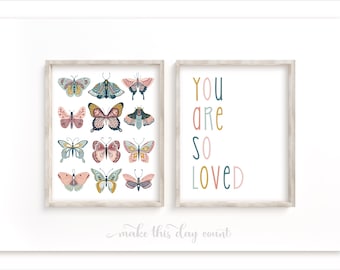 Könnte beinhalten: Zwei gerahmte Drucke, einer mit einem bunten Schmetterlingsdesign und der andere mit dem Text "YOU ARE SO LOVED" in einem Regenbogen von Farben.