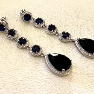 May include: A white ceramic mug with a black handle and the text "But First, Coffee" in a black, handwritten-style font. The mug is on a white surface.