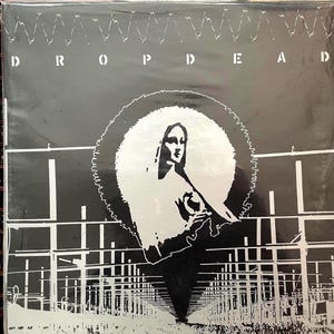 May include: Black and white album cover with the text "DROP DEAD" at the top. A stylized image of a woman in a halo with a black and white background.