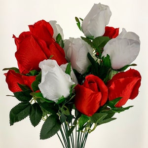 May include: A bouquet of artificial roses in red and white colors. The roses are arranged in a cluster with green leaves and stems.