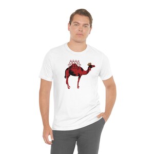 May include: A white t-shirt with a red camel silhouette graphic. The camel has a decorative design on its back and a brown hump.