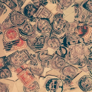 May include: A collection of vintage postage stamps, featuring various designs and colors, scattered across a surface. Some stamps are affixed to torn pieces of envelopes, creating a nostalgic and historical aesthetic.