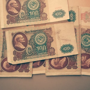 May include: A collection of vintage Soviet Union banknotes, each featuring a portrait of Vladimir Lenin and the text "Сто рублей" (One Hundred Rubles). The banknotes are in various states of wear and tear, with some showing signs of fading and discoloration.