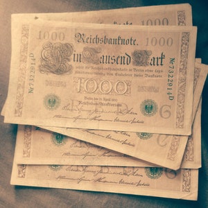 Peut inclure: Une pile de billets de banque allemands Reichsbank vintage, chacun comportant le texte "1000 Mark" et la date "Berlin, den 21. April 1910".