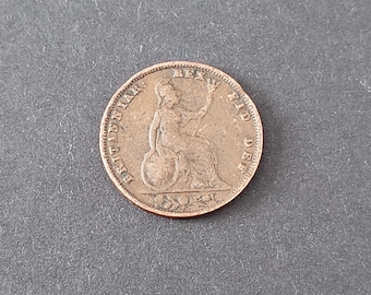 May include: A circular copper-colored coin featuring a seated figure holding a trident and shield. The text BRITANNIA: REX FID DEF is embossed around the perimeter. The coin has a worn, metallic surface with raised details and a beaded border.