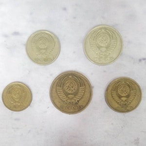 May include: Five Soviet Union coins featuring the hammer and sickle emblem and the inscription "CCCP". The coins are of varying sizes and shades of gold.