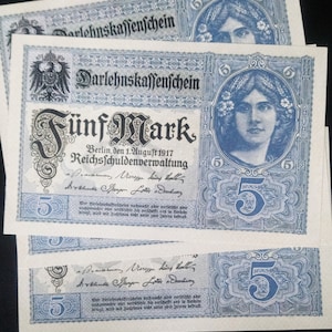 Könnte beinhalten: Drei deutsche Fünf-Mark-Darlehnsscheine vom 1. August 1917 mit dem Text "Darlehnskaffenchein Fünf Mark" und "Reichsschuldenverwaltung" in blauer und schwarzer Schrift.