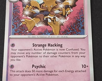 May include: A purple Alakazam trading card with 140 HP, featuring the character holding two silver spoons. The card displays the attacks Strange Hacking and Psychic, with text detailing the character's intelligence and the 2024 copyright information.