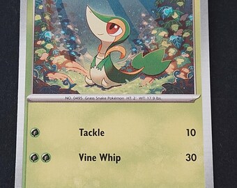 May include: A Snivy trading card featuring a green and cream-colored grass-type creature with red eyes. The card displays 70 HP, the attacks Tackle and Vine Whip, and text stating it is a Grass Snake Pokémon, 2 feet tall, weighing 17.9 lbs.