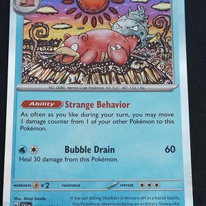 May include: A Slowbro trading card with 100 HP, featuring a pink creature with a Shellder on its tail. The card displays the Ability Strange Behavior and the attack Bubble Drain, with text detailing its evolution from Slowpoke and stats.