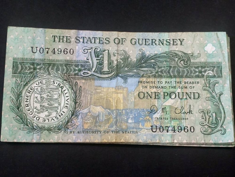 May include: A green and white banknote from the States of Guernsey with the text "THE STATES OF GUERNSEY" and "ONE POUND" printed on it. The serial number is U074960.