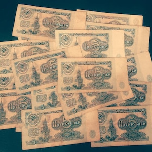 May include: A collection of vintage Soviet five ruble banknotes. The banknotes are in various states of wear and tear, with some being more faded than others. The banknotes feature a portrait of Vladimir Lenin and the text "Пять рублей" (Five rubles).