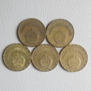 Könnte beinhalten: Fünf goldfarbene Münzen mit der Aufschrift "MAGYAR NÉPKÖZTÁRSASÁG" am Rand. Die Münzen zeigen ein zentrales Design eines Schildes mit einem Stern darüber.