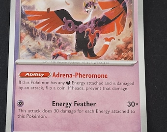 May include: A Fezandipiti trading card with 120 HP, featuring a purple and orange bird-like creature with wings spread. The card displays the Adrena-Pheromone ability and Energy Feather attack, with text detailing its stats and game mechanics.