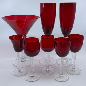May include: Set of eight red glass drinking glasses, including a martini glass, champagne flutes, and wine glasses.