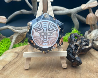 May include: A hexagonal resin coaster with a black background and gold flecks. The coaster features a white and copper-colored circular maze design in the center.