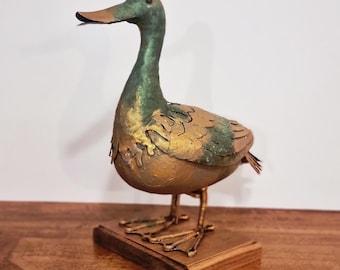 Pato señuelo de metal vintage sobre pedestal de madera