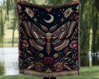 May include: A dark blue woven tapestry featuring a large, detailed moth with intricate wings and a crescent moon. The moth is surrounded by floral designs in shades of red, yellow, and gold.
