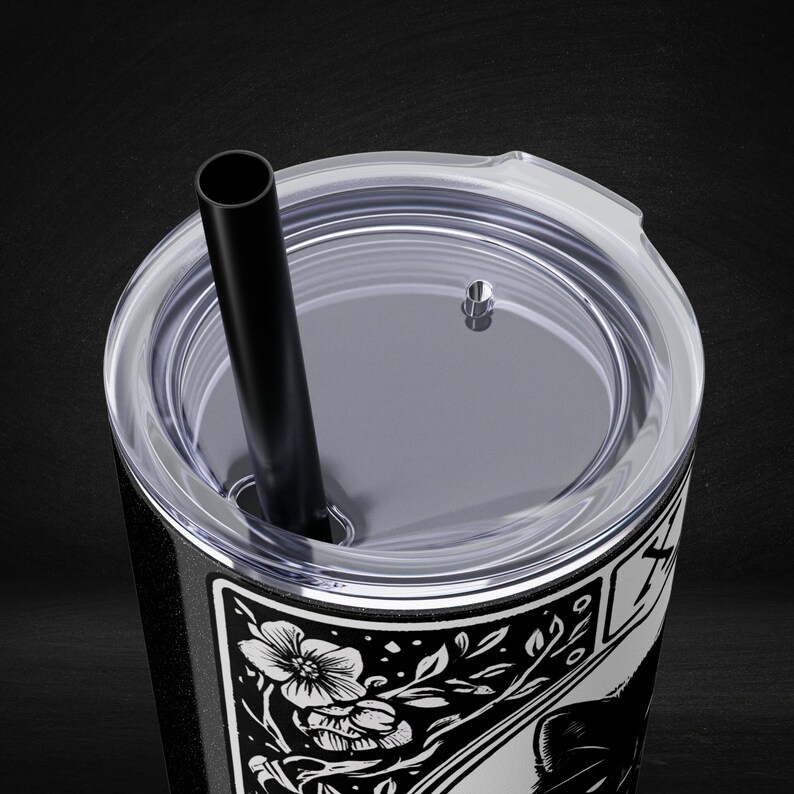 a black and white picture of a cup with a straw in it