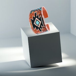 May include: A copper cuff bracelet with a geometric design in black, turquoise, and orange. The design features a central diamond shape with a turquoise stone.