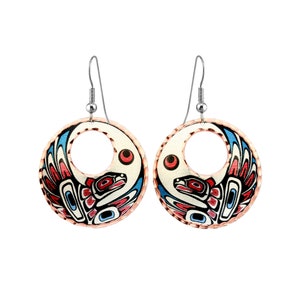 May include: A pair of copper-colored earrings with a circular design. Each earring features a white background with a red, blue, and black bird design. The earrings have silver-colored hooks.