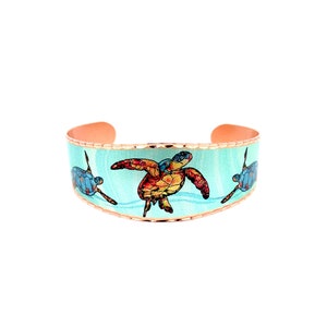 May include: Copper cuff bracelet with a turquoise blue enamel background and three colorful sea turtle designs.
