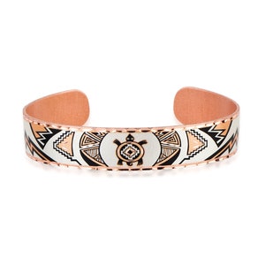 May include: A copper bracelet with a white and black geometric design featuring a turtle in the center. The bracelet has a rose gold finish.