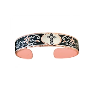 May include: A black and silver copper bracelet with a floral design and a cross in the center. The bracelet is accented with rose gold.