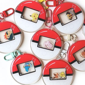 May include: Eight red and white Pokeball keychains with different Pokemon characters inside. Each keychain has a silver ring and a clear plastic cover.