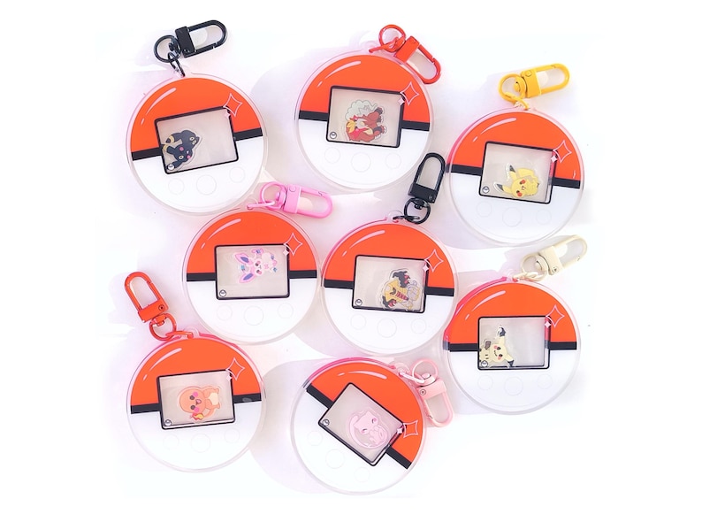 May include: Seven colorful keychains with round, transparent plastic cases featuring different Pokemon characters. Each keychain has a red, white, and black design with a Pokeball graphic.