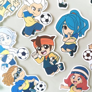May include: A set of nine colorful cartoon stickers featuring characters playing soccer. The characters are wearing yellow and blue uniforms and have different hairstyles and facial expressions. Each sticker includes a soccer ball.