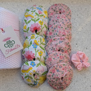 Puede incluir: Una colección de artículos de tela hechos a mano, que incluyen posavasos con estampado floral y una flor de tela rosa. Los posavasos presentan varios patrones florales con acentos rosas, amarillos y azules. También es visible una etiqueta con el texto "Fatinia Di".